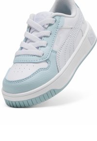Fehér és világoskék sportcipő, amely bőrből és szintetikus anyagokból készült, struktúrált felülettel, perforált orral és lapos gumitalppal.