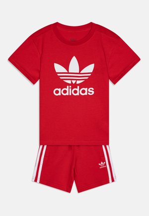 Rood katoenen sportset bestaande uit een t-shirt met wit adidas-logo en bijpassende shorts met witte zijstrepen en logo op de zoom.