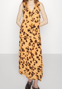 Robe imprimée léopard en orange et marron, avec un haut à volants sans manches et un design de jupe à niveaux. Tissu doux avec une coupe fluide.