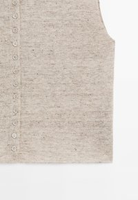 Gilet beige en maille sans manches avec une rangée verticale de petits boutons assortis le long du côté gauche devant.