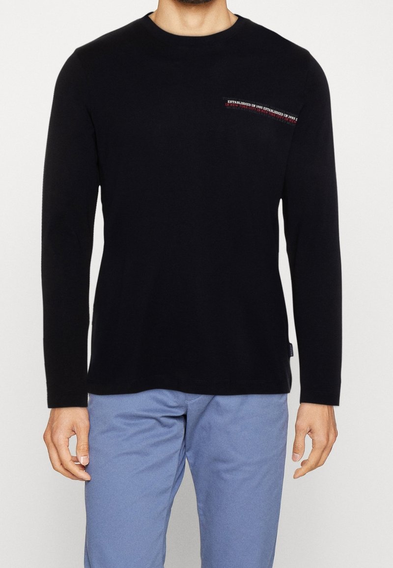 Schwarzes Langarm-T-Shirt aus Baumwolle mit kleinem gesticktem Logo auf der Brust. Weicher Stoff; klassisches Rundhals-Design.