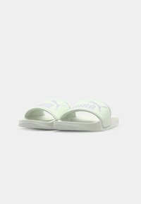 Ljusgröna halksandaler med ett brett band som har en vit Puma-logotyp och ljuslila detaljer, texturerad yta och mjuk sula.
