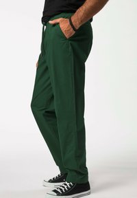 Vihreät, kevyet housut, joissa on joustava vyötärö ja naru. Malleissa on sivutaskut ja rento istuvuus. Yhdistetty mustiin lenkkareihin.