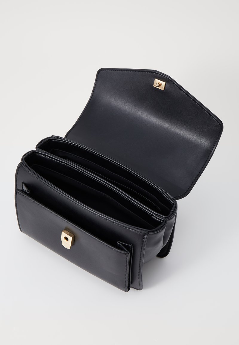 Sac à main en cuir noir avec un design structuré, matériel doré, trois compartiments intérieurs et une fermeture à pression magnétique.