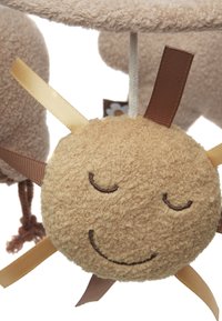 Plush sun toy with a textured beige surface, smiling face, and sewn features. Yellow and brown ribbons extend from the sides.