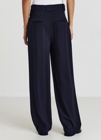 Pantaloni a gamba larga blu navy con un motivo a coste testurizzato, dotati di una vita alta, tasche posteriori e una vestibilità comoda intorno alle gambe.