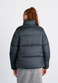 Giubbotto trapuntato nero con colletto alto, design a righe orizzontali e polsini elastici. Perfetta texture liscia con una finitura elegante.