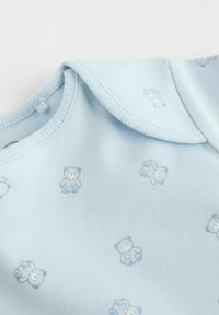 Un body en coton bleu clair avec de petits imprimés de teddy bears gris et bleus. Col rond avec une texture douce et des détails de couture délicats.