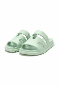 Sandalias moldeadas de color verde claro, con punta abierta, diseños recortados y dos correas ajustables. Hechas de material flexible y suave.