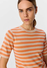 Maglione a maniche corte a righe in arancione e crema. Presenta un colletto rotondo e un tessuto a maglia morbido e texturizzato.