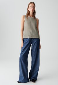 Mouwloze gestreepte top in beige en donkergroen, gecombineerd met wijde donkerblauwe denim broek. Vriendelijke textuur, minimalistisch ontwerp, casual stijl.