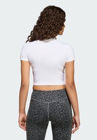 Biely skrátený tričko s krátkymi rukávmi v kombinácii s čiernymi legínami s vysokým pásom so vzorom leoparda.