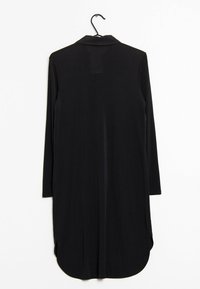 Czarna sukienka z długimi rękawami i kołnierzykiem wisząca na haczyku, z zaokrąglonym dołem i bocznymi rozcięciami, prezentowana na białym tle.