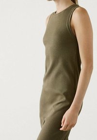 Robe sans manches côtelée vert olive avec une silhouette cintrée. Encolure légèrement arrondie et texture lisse, arrivant à mi-cuisse.