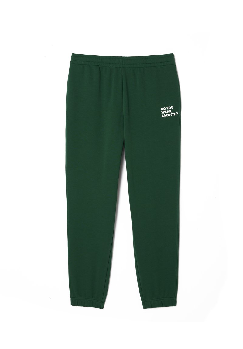 Zielone dresy wykonane z miękkiej tkaniny z elastycznym pasem i mankietami. Na prawej nogawce nadrukowany tekst: "CZY MÓWISZ LACOSTE?".