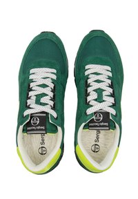 Une paire de baskets de sport vertes et jaunes avec des lacets blancs et des étiquettes de marque noires, présentées debout, vues de dessus.