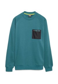 Sudadera de color azul verdoso con escote redondo, mangas raglán y un bolsillo negro que lleva el texto "CONVIÉRTETE EN UNA LEYENDA." Tejido suave con una textura lisa.