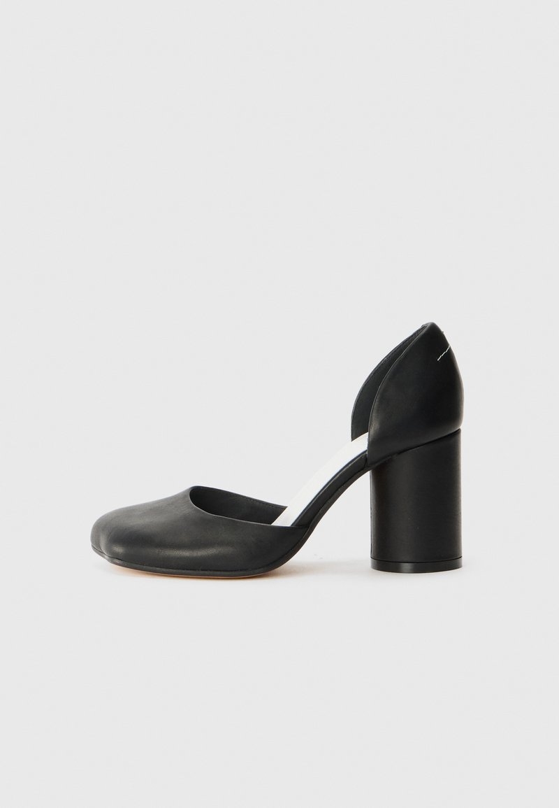 Black leather high-heeled pump with a rounded toe, cutout sides, and a chunky heel. Smooth texture with minimal detailing.