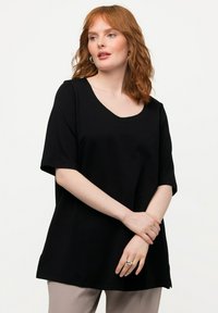 Schwarzes kurzärmliges T-Shirt mit V-Ausschnitt, aus weichem Stoff gefertigt, mit lockerer Passform und seitlichen Schlitzen für mehr Bewegungsfreiheit.
