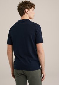 Polo de manga corta en color marino, confeccionado en tejido de punto, con cuello clásico y puños ribeteados, un dobladillo recto y un diseño de hombros sin costuras.
