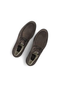 Une paire de chaussures mocassins en suède brun avec des lacets noirs et une doublure en fourrure crème, vue de dessus sur un fond blanc.