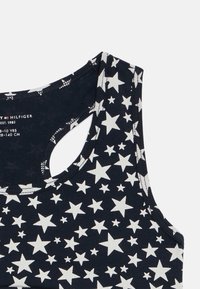 Mørkeblå tank top med hvit stjernemønster, med rund utringning, ermeløs design og en liten utskjæring bak.