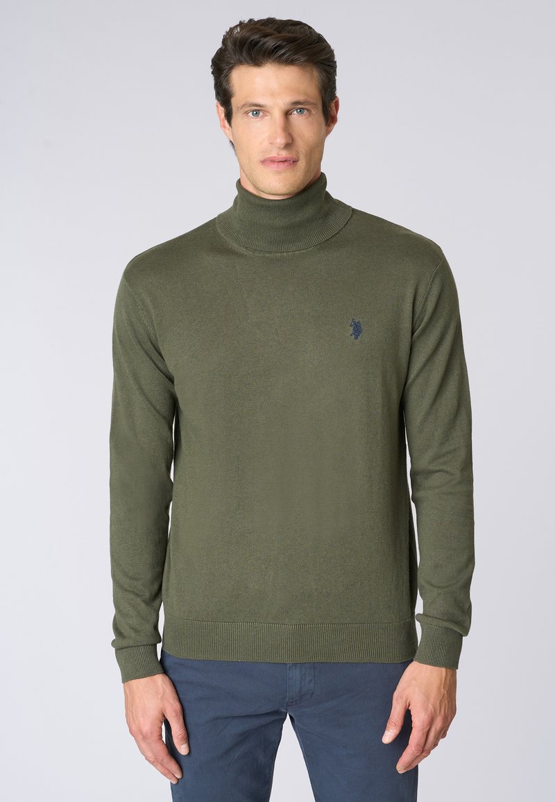 Maglione verde oliva a collo alto realizzato in morbido tessuto a maglia, con maniche lunghe e orlo a costine, dotato di un piccolo logo ricamato sul petto.