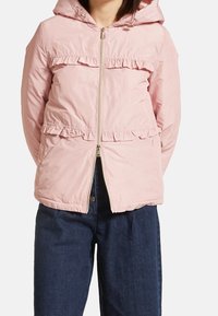 Rosa huva-jacka med rynkor längs fram och nederkant, med dragkedjestängning och rynkad midja. Lättviktig, slät tyg.