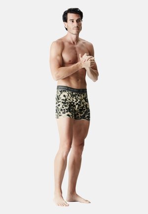 Boxers pour hommes en tissu doux avec un motif camouflage, dotés d'une ceinture noire sur laquelle figure le nom de la marque "pierre cardin." Design ajusté.