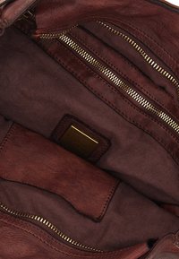 Interno di borsa a tracolla in pelle marrone con cerniere dorate, fodera in tessuto e una piccola etichetta in pelle. Molti scomparti per una conservazione organizzata.