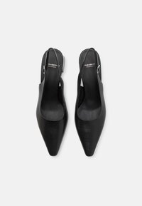 Black leather slingback heels with a pointed toe design. Features a slim heel and cut-out sides, with a buckle accent on the strap.