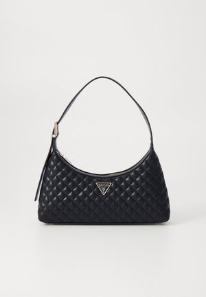 Sac à épaule en cuir matelassé noir avec un emblème triangulaire du logo Guess et une fine bandoulière réglable sur fond blanc.