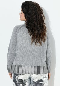 Maglione grigio a maglia con orlo e maniche a coste. Presenta una vestibilità rilassata, scollatura rotonda e tessuto texturizzato. NON visibile: parte inferiore dell'outfit.