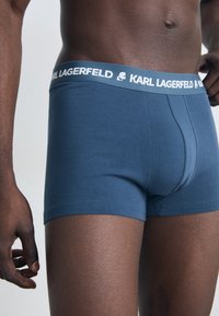 Boxeri de culoare bleumarin, confecționați dintr-un material moale, având un tiv alb inscripționat cu marca "KARL LAGERFELD" și un design ajustat.