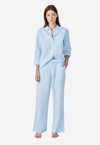 Lichtblauw, overhemd met lange mouwen en knoopsluiting, met een borstzak, gecombineerd met losse, elastische broeken. Zachte, gestructureerde stof.