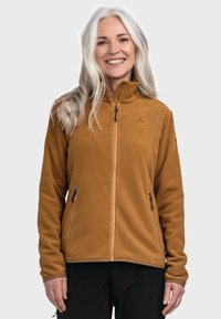 Braune Fleecejacke mit hohem Kragen, Reißverschluss vorne und zwei seitlichen Reißverschlusstaschen. Mit einem minimalen Logo auf der linken Brust.