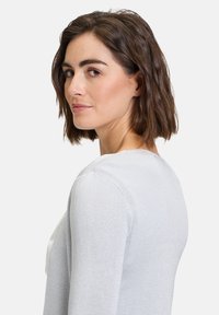 Maglione grigio chiaro realizzato in un tessuto texturizzato, con scollatura rotonda e maniche lunghe, che presenta un design semplice senza decorazioni.