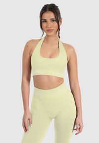 Top corto halter de color verde claro y con canalé, combinado con leggings de cintura alta. Ambos presentan el logotipo "SMILS" en blanco contrastante en la cinturilla.