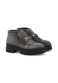 Stivaletti alla caviglia in suede grigio con suole nere spesse e dettagli in oro a forma di morso sul davanti, mostrati affiancati su uno sfondo bianco.