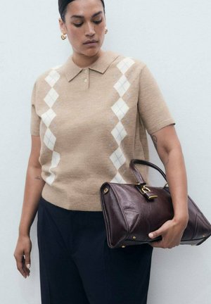Persoon in een beige argyle-patroon korte mouwen trui en donkere broek, met een donkerbruine leren handtas met gouden hardware.