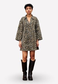 Leopardprint jurk met een V-hals en lange mouwen, gemaakt van zachte stof. Draag met kniehoge zwarte laarzen.