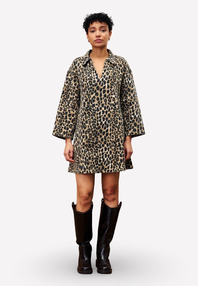 Leopardprint jurk met een V-hals en lange mouwen, gemaakt van zachte stof. Draag met kniehoge zwarte laarzen.