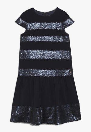 Schwarzes kurzärmliges Kleid mit horizontalen silbernen Paillettenstreifen und einem gerafften Rocksaum, der mit silbernen Pailletten verziert ist.