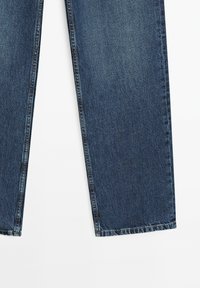 Jeans in denim blu scuro con un design a gamba dritta, caratterizzati da dettagli di cucitura e orlo pulito. Il materiale ha una leggera texture e una sfumatura.