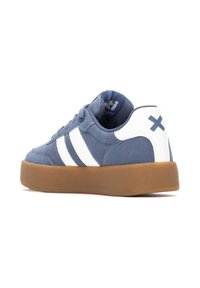 Zapatillas de ante azul con rayas blancas y un acento en el talón blanco, que cuentan con una suela de goma y un cuello acolchado para mayor comodidad.