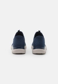 Navy blue slip-on shoes with a textured, diamond-patterned upper, rubber soles, and fabric loops at the heel for easy wear.