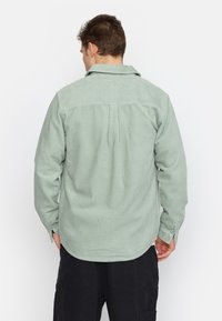 Groen gestreepte corduroy shirt met een spread collar, lange mouwen en knoopmanchetten. Bevat een yoke en achterplooidetails.