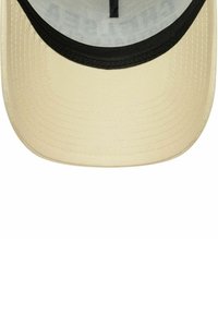 Casquette de baseball beige avec une visière courbée et doublure intérieure noire visible à l'intérieur de la couronne.