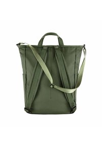 Sac à dos en tissu vert avec deux poignées supérieures, des bretelles ajustables et des fermetures à bouton. Texture lisse avec une forme rectangulaire.