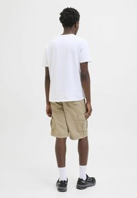 White short-sleeve T-shirt, khaki cargo shorts with side pockets, black sneakers, white ankle socks, viewed from the back against a neutral background.